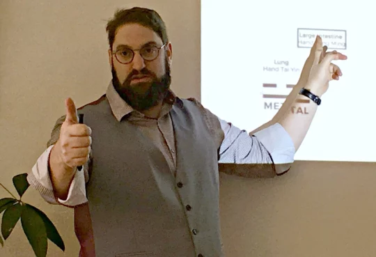 Jonathan Shubs teaching a course, pointing to a slide on the lung and large intestine channels